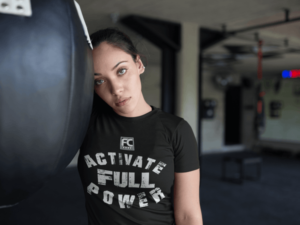 Female in the Gym  working out taking a break wearing a black t-shirt with grunge Activate Full Power design available from the Xpert Apparel Store 