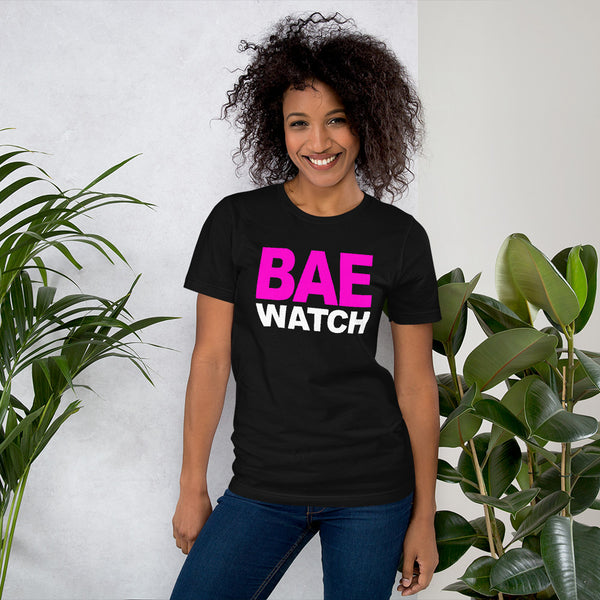 Woman Poseing in front of potted plants in black T-shirt with "Bae Watch" design from the Xpert Apparel Store