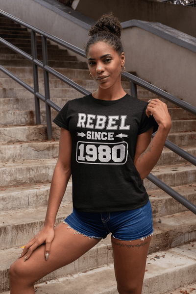 Woman Standing on Stairs in short jeans shorts and a black t-shirt with "Rebel since 1980" design from the "Xpert Apparel Store"