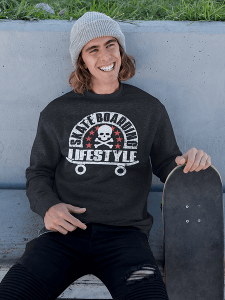 Young man sitting on side walk with his skateboard by his side wearing black t-shirt/Sweater with "Skateboarding Lifestyle" design on the front available from the Xpert Apparel Store.