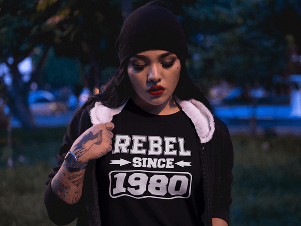 Hispanic Lady with towel over shoulder wearing a Black T-shirt with "Rebel since 1980" design from the Xpert Apparel Store 