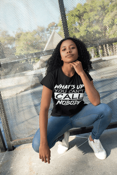 Beautiful young lady stooping down wearing blue jeans and Black T-shirt with "Whats's up you can't call nobody now available from the Xpert Apparel Store