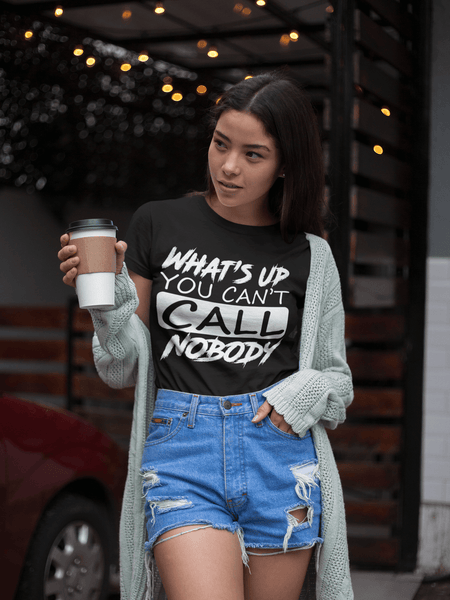 Beautiful young lady holding cup of coffee wearing blue jeans shorts and Black T-shirt with "Whats's up you can't call nobody now available from the Xpert Apparel Store