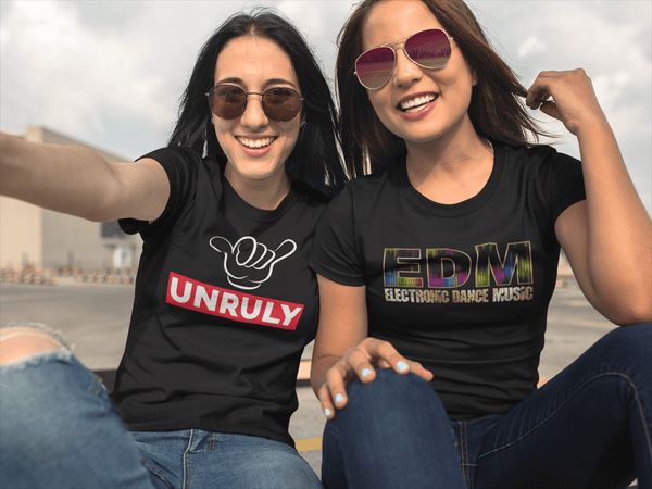 Two woman friends sitting taking a selfie bothe wearing black t-shirt one with unruly  and the other with EDM design on the front available from the Xpert Apparel Store